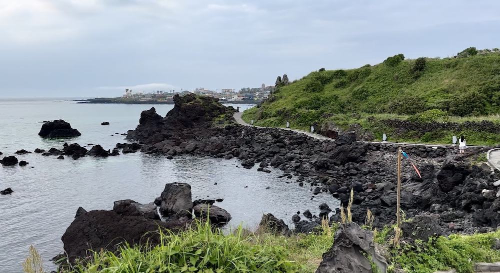 Cement walking trail with black lava rocks and green hills - Handam Coastal Walk in Jeju Island - best things to do in Jeju