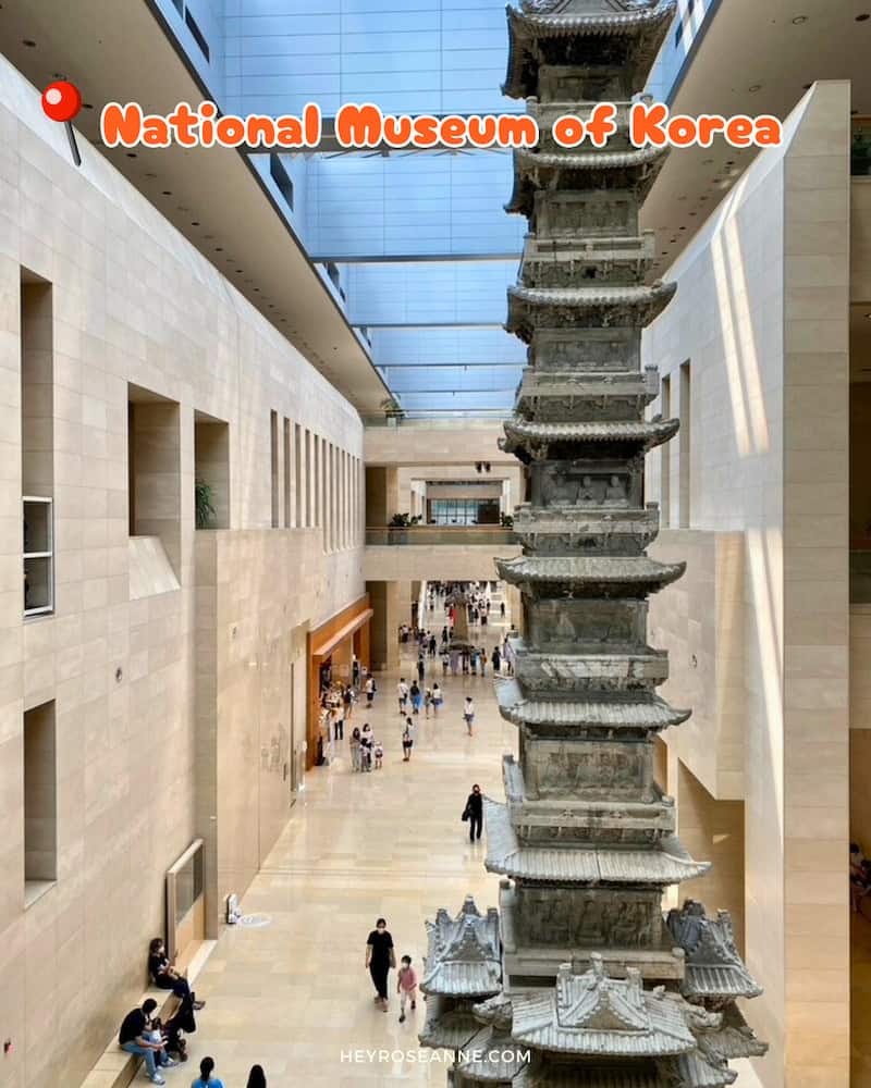 National Museum of Korea in Seoul: An interior view of the National Museum of Korea, showcasing a large, intricately detailed stone pagoda as the central feature in a spacious, light-filled hall. Visitors are seen walking and exploring the museum, highlighting the grand scale of the structure and the modern architectural design that frames this historical artifact. The image includes text indicating the location as the "National Museum of Korea."