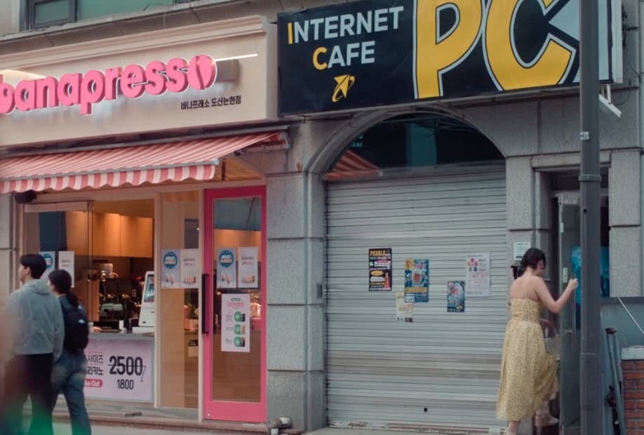 The iconic statue of King Sejong in Gwanghwamun Square, with the backdrop of the Seoul skyline and mountains, a notable scene from "XO, Kitty" Season 2.